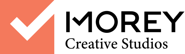 Morey Creative Studios Logo Orange box with checkmark cutout, with dark grey text that says Morey Creative Studios